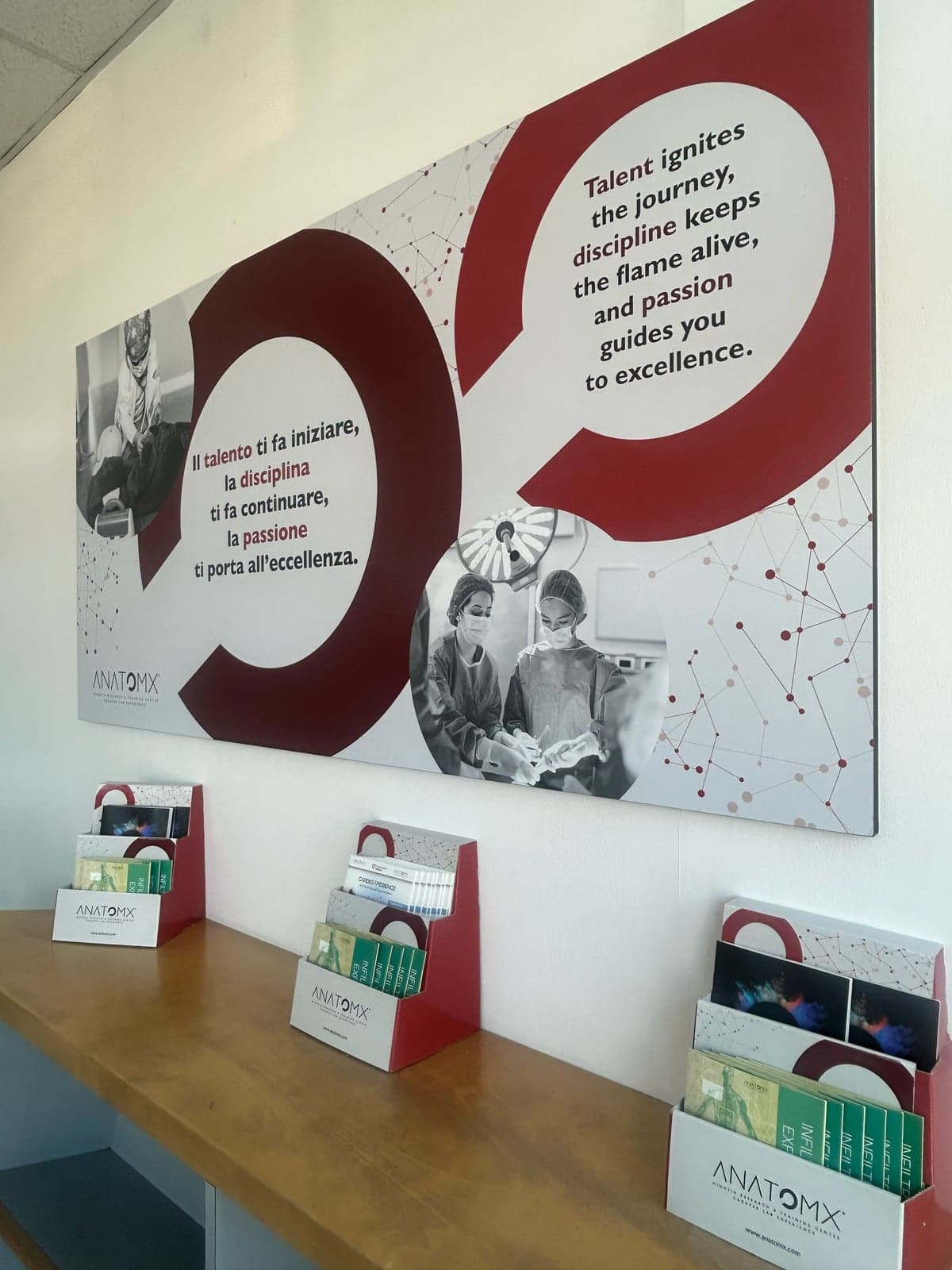 Wall panel with the centre's mottos above a rack of AnatomX brochures