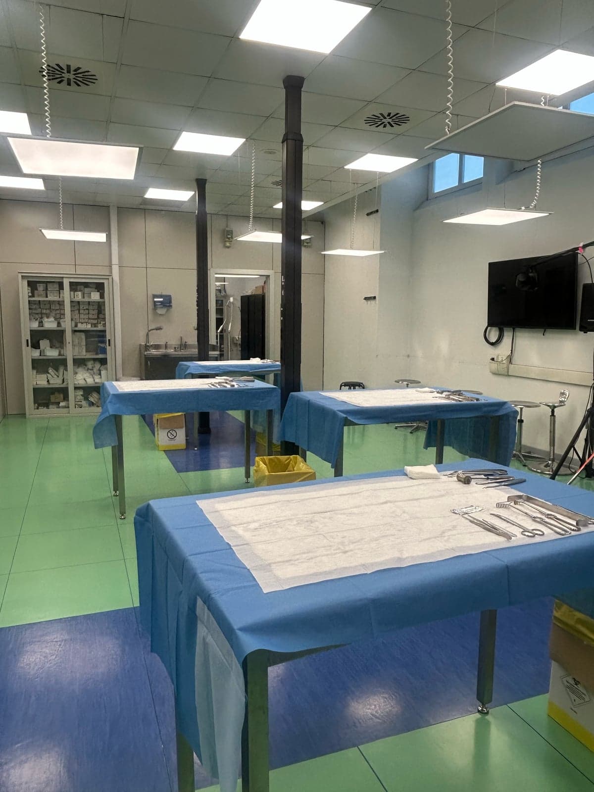 Dissection room with tables under blue drapes, set out with instruments